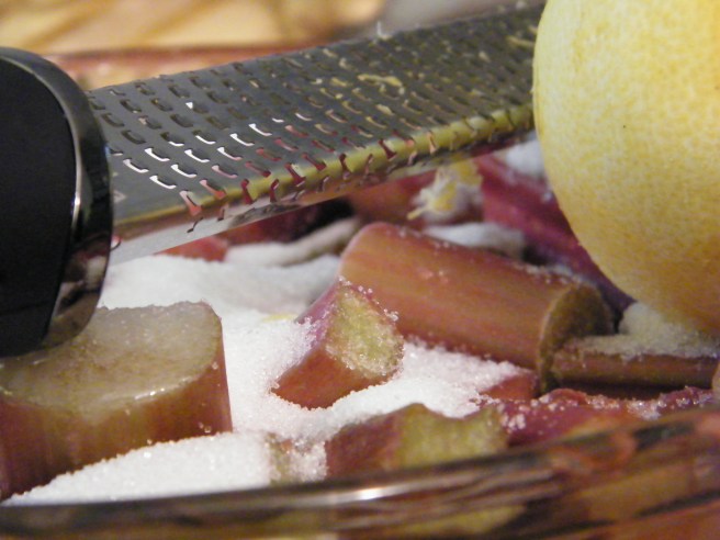 Rhubarb in a field of sugar, with a partly zested lemon and (unsurprisingly) a zester.