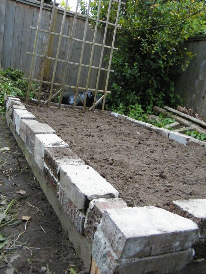 A raised garden bed made with bricks laid on top of two-by-fours, with a wooden trellis on one end. A raised garden bed made with bricks laid on top of two-by-fours, with a wooden trellis on one end.