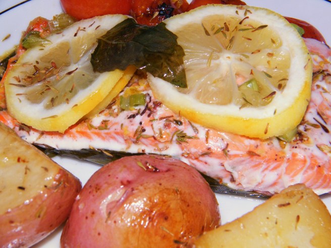 The salmon, with the grape tomatoes in the background and roasted potatoes in the foreground.