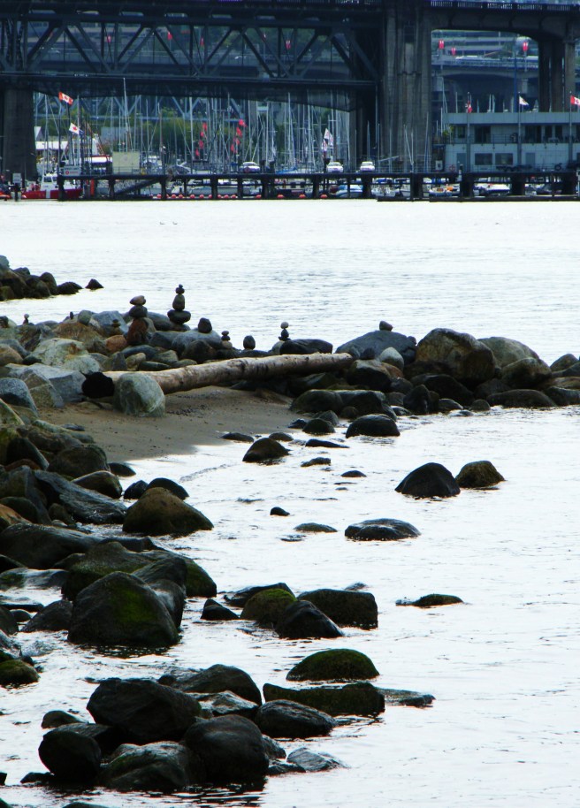 Rocks along the ocean, with a marina and a bridge across the water.