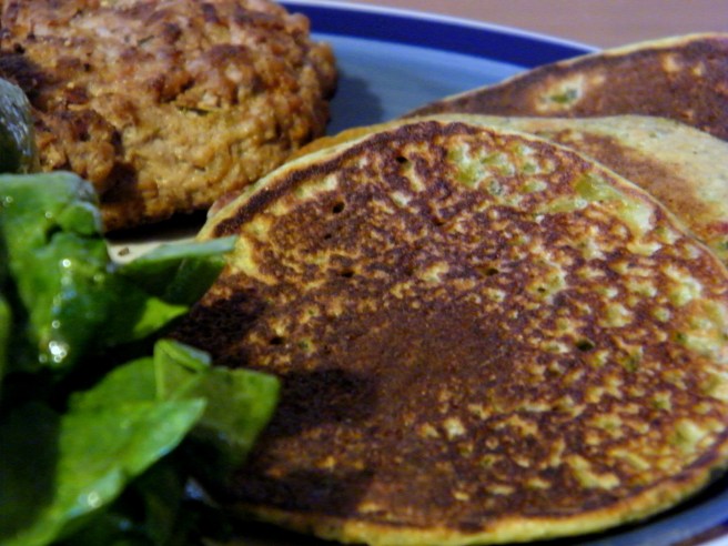 Swiss chard pancakes with lamb burgers and spinach salad, on a blue plate with a darker blue stripe around the edge.